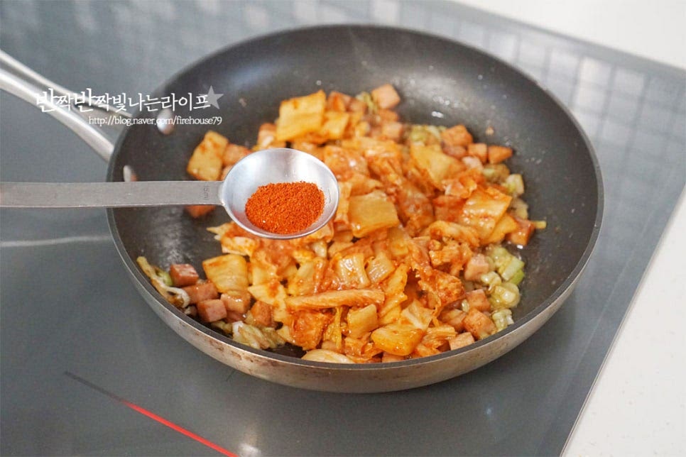 지글지글 풍미를 살려준 뒤 썰어둔 김치와 고운 고춧가루 1/3 큰 술 넣어줍니다. 매콤하면서 빨간색이 곱게 어우러져요. 타지 않도록 중약 불로 불 조절을 하고 양념재료가 뭉치지 않게 볶아줍니다. 수분이 부족하다면 물을 조금 추가해도 좋아요. 골고루 볶아지면 찬밥을 넣고 섞어요. 즉석밥은 데우지 않고 그대로 넣고, 지은 밥은 열기를 한 김 식혀 넣어주어 고슬고슬한 식감을 살려줍니다. 밥알이 풀어지도록 볶아줍니다. 간이 골고루 어우러지도록 센 불로 휘리릭 볶은 뒤 통깨를 넣고 마무리해요. 저는 참기름 약간 더해주었습니다~ 백종원님이 알려주는 파는 맛 내는 팁 흰색 MSG를 약간 더해주면 된다고 해요.