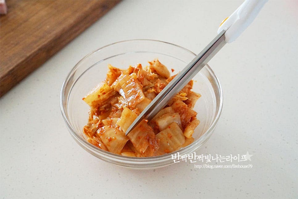 메인 재료는 잘 익어 숙성된 신 김치로 준비해 줍니다. 새콤하게 익은 것이어야 볶았을 때 깊은 맛이 납니다. 염도에 따라 양을 조절해 주시면 되고 깔끔한 맛을 위해 김칫소는 덜어내어 주었어요. 도마에 빨간국물이 묻어나지 않도록 간편하게 가위로 한 입 크기로 잘라줍니다. 스팸은 염도가 낮은 것을 준비했는데요. 불순물 제거를 위해 뜨거운 물을 부어 가볍게 헹구어주었습니다. 물론 그대로 잘라 넣어주셔도 좋습니다. 한입에 먹기 좋도록 깍둑썰기해주고, 대파는 파기름을 내어줄 것이라 흰 부분 위주로 잘게 송송 썰어주었어요.