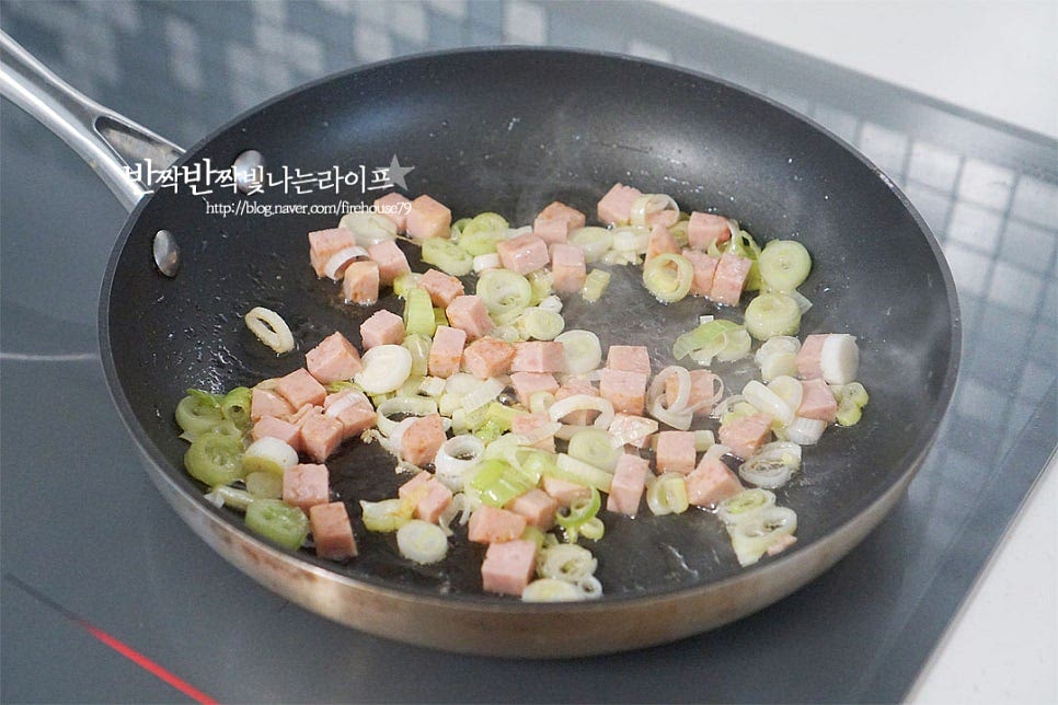 달군 팬에 식용유 3 큰 술을 두른 뒤 대파와 스팸을 넣고 볶아줍니다. 동물성 재료인 햄종류를 먼저 기름에 넣고 볶아 고소한 풍미를 살려주는데요. 파와 같이 넣고 볶아 향을 살려주는 것이 백종원 스팸김치볶음밥 레시피 포인트입니다. 노릇노릇하게 볶아지면 황설탕 1/3 큰 술을 넣어요. 약간 눌어붙도록 볶아주어 나중에 김치의 새콤한 신맛을 잡아주고, 단맛 감칠맛을 더해준답니다. 익은 정도에 따라 단맛은 가감해 주시면 됩니다. 설탕이 녹으면 진간장 1/2 큰 술 넣어주어요. 수분이 사라지도록 향을 내어 볶아줍니다.