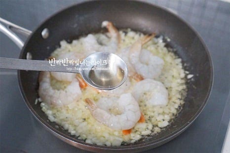새우를 넣고 화이트와인 1/2 큰 술을 뿌려줍니다. 와인 대신 청주나 맛술도 좋으며 많이 들어가면 쓴맛이 날 수 있으니 비린내를 잡아줄 정도로 소량 넣어주세요. 먹기 좋게 익으면 3~4개는 그릇에 따로 덜어 담아두고 마지막에 예쁘게 플레이팅 해줄 것입니다.