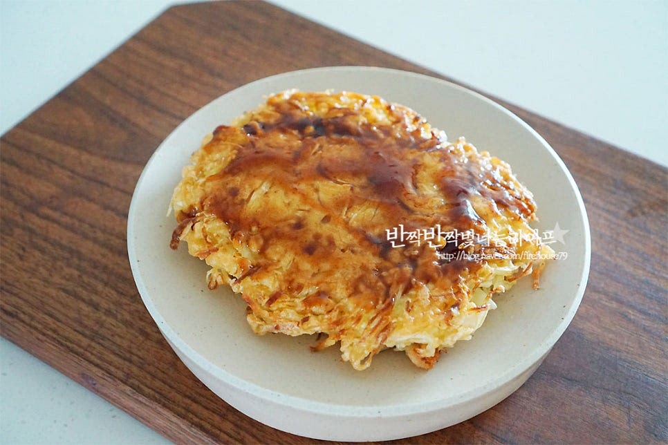 그릇에 담은 뒤 소스를 발라줍니다. 전용소스를 사서 발라주었는데 없다면 돈까스소스에 케첩을 약간 더해 섞은 뒤 발라주시면 되어요. 오꼬노미야끼 만들기 빠질 수 없는 조합이 바로 마요네즈죠. 마요네즈가 같이 올라가야 맛이 완성된답니다. 전용 용기나 짤주머니로 뿌려주면 먹음직스럽게 담을 수 있어요. 가쓰오부시와 실파를 올리고 파슬리가루도 약간 더해주었어요. 가쓰오부시를 올리면 살랑살랑 춤을 추는 것 같이 움직여 한맛 더 맛있게 즐길 수 있어요~ 영상도 같이 담았어요. 바로 구워서 먹는 맛은 겉은 바삭, 속은 촉촉 식감은 아삭아삭, 쫄깃한 게 색다른 별미를 맛볼 수 있답니다. 아이도 좋아하고 술안주로도 정말 잘 어울려요. 오코노미야끼 식감 살려 만들어 색다른 양배추전을 즐겨 보아요. 맛있게 만들어 드세요^^ 끄읕 !