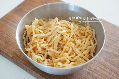 염장상태의 해파리는 먼저 짠맛을 빼주고 냄사가 나지 않고 식감을 살려 손질해 주는 과정이 냉채를 만드는 데 중요합니다. 넉넉한 크기에 볼에 잠길 정도로 물을 담고 1시간 정도 소금기를 제거해 줍니다. 겉의 짠맛을 먼저 털어주기 위해 가볍게 두세 번 헹군 뒤 담가주었어요. 너무 오래 담그면 퍼지거나 되려 싱거워질 수 있어 중간에 맛을 확인한 뒤 짠맛을 빼는 시간을 조절해 주세요. 염분을 제거한 뒤 가볍게 데쳐줍니다. 먼저 냄비에 잠길 정도로 물을 부어 끓여주는데요. 이때 물의 온도는 뜨겁지 않은 따뜻한 60~70도 온도로 기포가 약간 올라오려고 할 때 불을 끄고 넣어줍니다. 자칫 너무 오래 데치면 고무줄같이 질겨질 수 있어 넣은 뒤 10초~30초 정도 빠르게 데쳐줍니다. 따뜻한 물에 넣으면 오그라드는 게 눈으로 보입니다. 뒤적여 빠르게 데친 뒤 찬물에 헹구어 주어요. 꼬들꼬들한 식감에 단촛물을 더해 새콤달콤한 감칠맛을 입혀줍니다. 황설탕 1 큰 술, 식초 1 큰 술 소금 한 꼬집을 넣고 조물조물 버무려 준 뒤 냉장고에 넣어 한두 시간 이상 차갑게 숙성하여 줍니다.