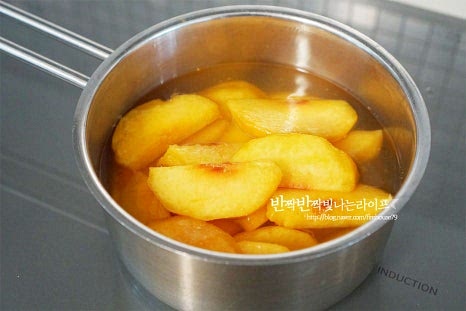 설탕이 녹고 다시 끔 끓어오르면 썰어둔 황도와 레몬즙 1 큰 술을 넣어줍니다. 레몬즙이나 레몬 조각이 조금 들어가면 색도 선명하고 상큼한 풍미를 더해 맛과 향도 좋으며 오래 보관할 수 있도록 해줍니다. 중간중간 떠오르는 거품은 걷어내면 깔끔하게 만들 수 있습니다. 끓어오르면 중불로 줄인 뒤 단단한 과육은 10~12분, 부드러운 것은 6~7분 정도 조림합니다. 끓이면서 졸아들면 과육이 투명빛이 돌면서 맛도 더 진해집니다. 부드러운 황도로 만들어 6분 정도 끓여 완성했습니다.