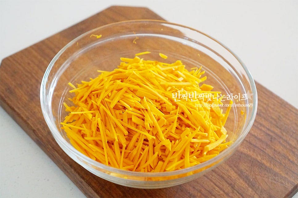 채 썬 호박을 볼에 담아줍니다. 이대로도 달아서 따로 간을 하지 않아도 되지만 단맛 감칠맛을 더해주기 위해 소금 한 꼬집 넣고 버무려주어요. 보통 부침가루에도 간이 되어있어 소금을 너무 많이 넣으면 짠맛이 많이 느껴질 수 있어요. 부침가루 1컵을 넣고 찬물을 부어가며 농도를 조절해 줍니다. 물을 한 번에 붓지 않고 넣어가며 농도를 조절하여 주시면 호박전 만들기 반죽 실패 없이 만드실 수 있어요. 우리 집 스타일은 반죽보다는 속 재료가 많은 걸 좋아해서 부침가루를 모양 잡기 좋을 정도로 맞추어 넣었어요. 기호에 따라 반죽 양은 조절해 주시면 입맛에 맞게 굽기 더 좋아요. 날가루가 보이지 않게 반죽을 잘 섞어주었어요.