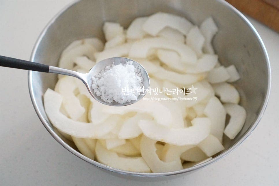 큼직한 크기의 볼에 손질한 노각을 넣고 소금 2/3 큰 술을 뿌려줍니다. 가볍게 버무려 절여줍니다. 대략 15~20분 정도 절여주세요. 중간중간 뒤적여 절여주면 늙은오이의 수분이 나오면서 식감이 아작아작해지고 탄력이 생깁니다. 절인 뒤 만들면 쓴맛도 잡아주고 물이 생기지 않고 식감도 좋아요. 절여진 오이노각은 소금기를 헹구어줍니다. 면보에 넣고 물기를 꼭 짜줍니다.