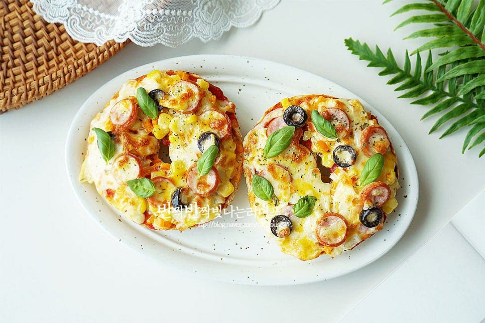 뜨거울 때 먹으면 바삭 쫀득하고 피자치즈가 늘어나는 고소한 풍미를 맛볼 수 있어요. 완성된 베이글피자에 바질잎을 올려 완성했어요. 영상도 같이 담았어요. 베이글 맛있게 먹는법은 크림치즈만 발라먹거나 샌드위치를 만들어도 맛있지만 단면을 잘라서 토핑을 곁들여 베이글피자를 만들어도 맛있어요. 토마토소스와 소시지, 콘, 치즈를 올려 구우면 간단한 레시피로 즐길 수 있어요. 간식이나 한끼 식사로 맛있게 만들어드세요. 끄읕 !