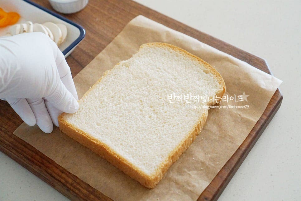 피자식빵 만들기는 간단한데요. 먼저 빵을 올려줍니다. 피자빵을 만들 때 또띠아나 밀가루 반죽으로 만드는 방법도 있지만 식빵을 활용하면 더욱 손쉽게 요리할 수 있어요. 식빵 1개당 마요네즈 1 큰 술을 골고루 발라줍니다. 그 위로 토마토소스를 발라줍니다. 시판용 소스 농도에 따라 양은 가감해 주고, 생토마토를 잘게 썰어 같이 넣어주면 산뜻한 풍미가 더 좋습니다. 셋, 토핑을 올려줍니다. 양송이버섯을 올린 뒤 그 사이로 준비한 모차렐라의 1/4 정도를 올려주었어요. 마지막에 피자 치즈를 올리기도 하지만 중간에 약간 넣어주면 재료가 더 잘 어울리고 고소하게 맛볼 수 있답니다. 소시지, 파프리카, 블랙 올리브를 올려주고요. 마지막으로 모짜렐라를 듬뿍 올려준 뒤 에어프라이어 바스켓에 담아줍니다. 구워지는 동안 재료가 흘러내리지 않도록 안쪽으로 토핑을 모아서 올려주는 게 좋아요.