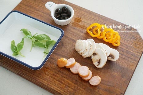 피자 토핑 재료를 먼저 준비해 줍니다. 식빵 위에 올려줄 것이라 적당히 작게 잘라주어야 흘러넘치지 않게 모양을 낼 수 있어요. 양송이버섯과 미니 파프리카, 소시지는 편으로 썰고 블랙올리브는 잘린 것을 준비했어요. 바질 잎은 찬물에 담가 물기를 제거해 줍니다.