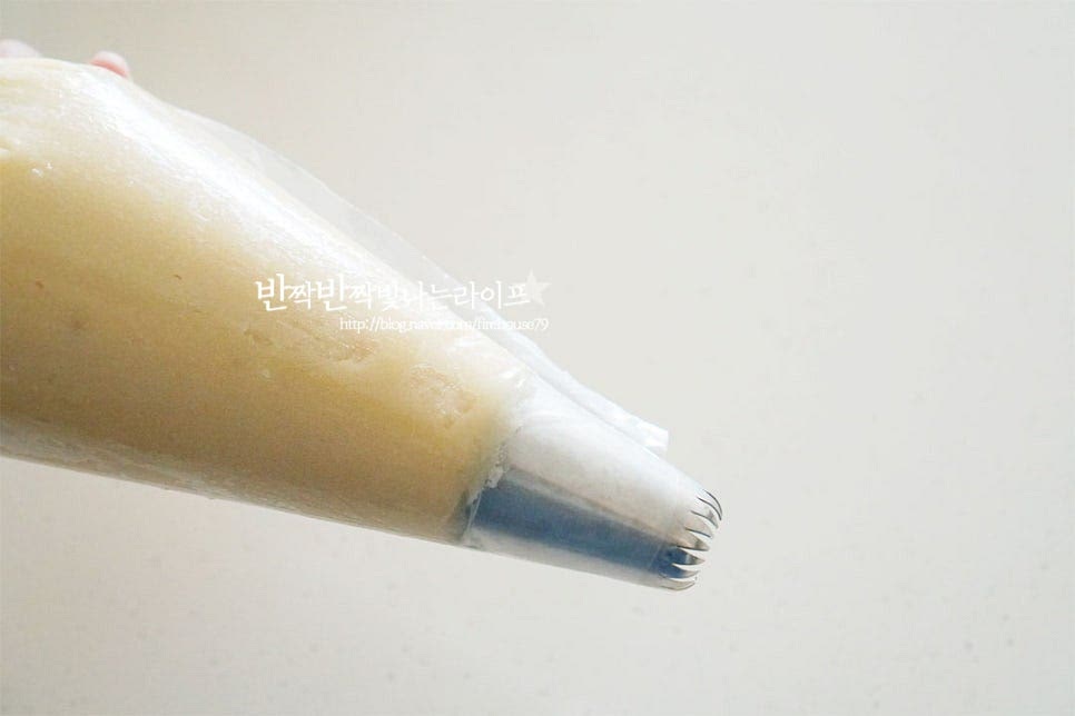 짤주머니에 깍지를 끼운 뒤 만들어둔 앙큼 쿠키 반죽을 넣어줍니다. 오븐 트레이에 일정한 크기로 짜줍니다. 서로 적당히 간격을 두르고 둥근 원뿔 모양을 만듭니다. 상투과자는 부풀거나 퍼지지 않아 붙지 않게 짜주면 됩니다.