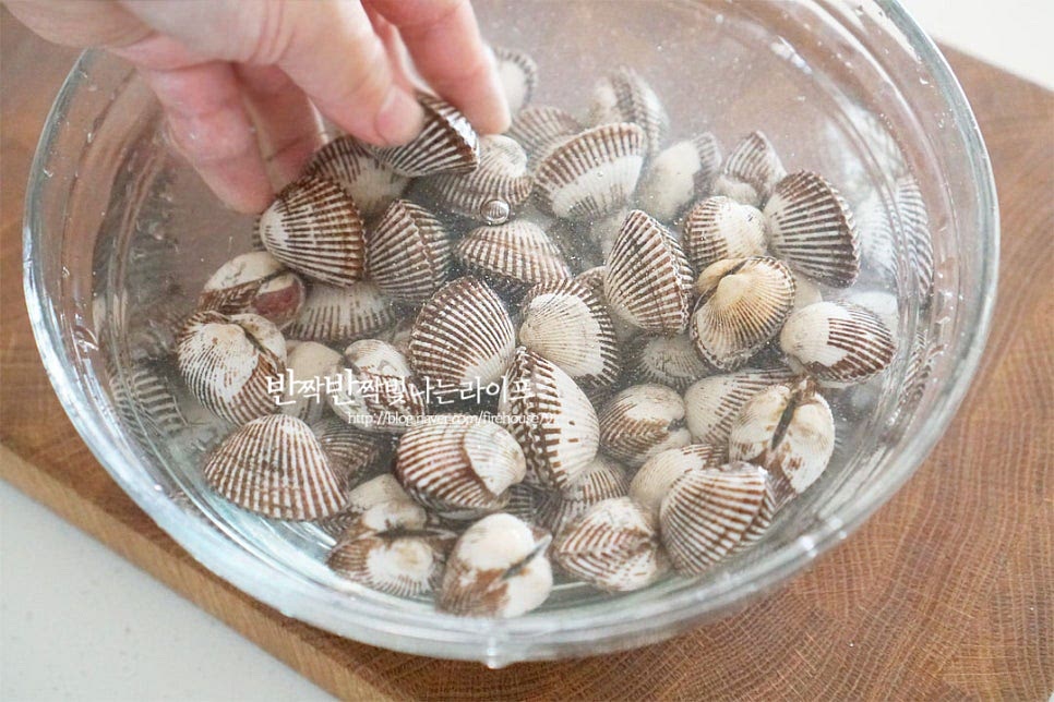 해감하기 전에 서너 번 흔들어 씻어줍니다. 생각보다 불순물이 꽤 많이 나와서 여러 번 헹구어 세척해 주었습니다. 너무 힘을 주면 껍질이 깨질 수 있으니 흔들어가며 씻어주면 됩니다. 스테인리스 냄비에 재료가 잠길 정도로 물을 붓고 소금 1 큰 술을 녹여줍니다. 짭조름한 농도로 소금물을 만들어 세척한 꼬막을 넣어줍니다. 뚜껑을 덮고 냉장고에 넣어 1시간 정도 해감해 줍니다. 스테인리스 소재를 사용하면 해감에 도움이 되는데 뚜껑이 있는 냄비를 사용하면 간편해요. 해감 후 다시 한번 세척해 줍니다.