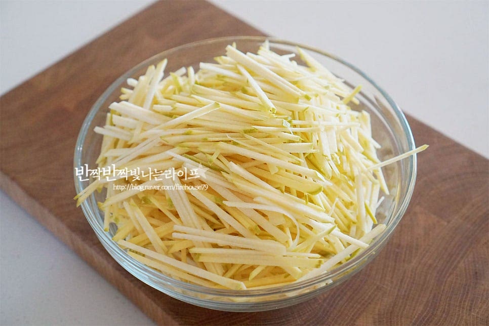 넉넉한 크기의 볼에 채 썬 과육을 담아요. 특유의 향긋함이 진해요. 겨우내 장기보관하여 먹는다면 과육 1 : 설탕 1 기본비율로 만들어주는게 좋은데요. 단맛을 줄이기 위해 설탕량을 70~80% 정도로 넣어주어도 좋습니다. 은은한 단맛이 나는 꿀을 넣으면 본연의 향과 잘 어울려 설탕을 50%, 꿀 50%을 넣어주었습니다. 같이 넣으면 보관하기도 좋고 숙성되었을 때 향긋하고 깊어요. 잘 어우러질 수 있도록 버무려줍니다. 수분이 적지만 꿀을 넣었기 때문에 실온에 한두시간 두면 잘 녹아있어요. 설탕 입자가 녹을 수 있도록 중간에 섞어주었습니다.