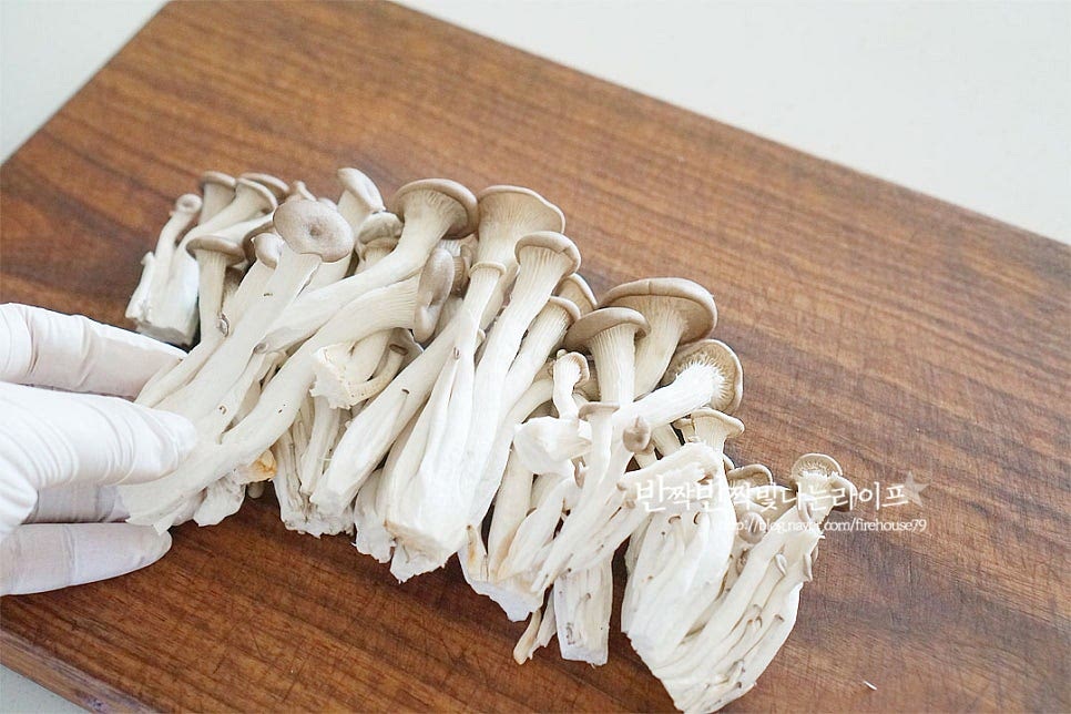 느타리버섯 요리를 만들기 앞서 식감을 살려 손질을 해주는데요. 갓이 부서지지 않게 살살 흔들어 씻은 뒤 밑동이 있다면 잘라내고 낱개로 분리하여 손질해 줍니다. 다른 종류에 비해 살이 연하여 상하기 쉬운 식재료로 가급적 빠른 시일 내 요리해 드시는 게 좋으며 보관 시에는 세척하지 않은 물기가 없는 상태로 키친타월에 감싸 냉장 보관해 줍니다. 끓는 물에 소금 1 작은 술을 넣고 가볍게 데쳐줍니다. 느티리는 데쳐서 손질한 뒤 전이나 무침, 볶음 등의 요리를 만들어 먹습니다. 오래 데칠 필요 없이 20~30초 내외로 숨이 죽을 정도로 데친 뒤 찬물에 헹구어 줍니다. 찬물에 헹구어 물기를 꼭 짜서 제거해 줍니다. 조리 후 보면 통통했던 기둥이 수분이 빠지면서 얇아지고 식감은 더 쫄깃해집니다. 길이에 따라 먹기 좋게 듬성듬성 썰어줍니다. 이렇게 수분을 제거한 뒤 느타리버섯전을 구워야 물이 생기지 않고 부침옷이 분리되지 않아요.