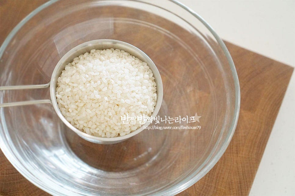 쌀의 품종에 따라 밥맛에도 차이가 있는데요. 혼합보다는 단일 품종으로 밥하는게 좋으며 쌀알이 조금 작은 종류는 물의 양을 조금 덜 잡아도 되기 때문에 구입할 때 확인해 보는 것도 좋을 것 같습니다. 넉넉한 크기의 볼에 쌀 2컵을 넣고 먼저 씻어줍니다. 첫물은 불순물이 많이 나오기 때문에 쌀알이 흡수하지 않도록 빠르게 헹구어 버리는 게 좋아요. 4~5번 손으로 섞듯이 저어가며 씻어 줍니다. 기본적인 불리는 방법은 물이 잠길 정도로 붓고 30분 불려주는 것인데 저는 쌀알이 작은 편이고 도정한지 얼마 되지 않을 쌀이라 가볍게 10분만 불려주었습니다. 불림 정도는 입맛에 따라 차이가 있기 때문에 시간을 조절하여 주고, 묵은쌀은 수분이 적기 때문에 꼭 불려서 밥을 짓는 것이 밥맛이 좋습니다. 정확한 계량을 위해서 계량컵을 사용하면 밥물을 실패 없이 맞출 수 있으며 불린 쌀은 체에 밭쳐 물기를 털어줍니다.