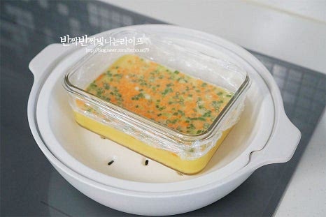 계란찜 중탕으로 조리하기 위해 김이 오른 찜기에 넣고 뚜껑을 덮어 중약 불로 20~25분 익혀줍니다. 찜기를 사용하지 않고 냄비로 요리할 때는 바닥면에 면포를 깔고 물을 부어 익혀주세요. 25분 가까이 익혀준 뒤 뚜껑을 열어보면 촉촉하게 잘 만들어졌어요. 익은 정도를 확인하고 싶다면 이쑤시개로 찔러보았을 때 달걀물이 묻어나지 않으면 됩니다. 뜨거우니 조심하여 꺼낸 뒤 넓은 접시에 밭쳐 분리해 줍니다. 참기름을 발라주었기 때문에 쉽게 분리되어요. 먹기 좋게 잘라줍니다. 급식에서 보던 네모난 모양으로 잘라주었어요. 계란물에 밑간해준 뒤 곱게 체에 내려 찜기를 활용하여 중탕으로 익혀주어 식감이 정말 부드럽고 촉촉한 푸딩 같은 맛이에요. 영상도 같이 담았어요. 급식에서 먹던 추억이 떠오르는 부드러운 계란찜 만들기 간단하고 든든한 추억의 맛이랍니다. 푸딩 계란찜 레시피로 부들부들 촉촉한 맛을 느껴보세요^^ 끄읕 !