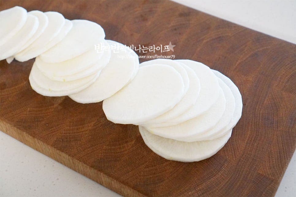 1.5kg 정도 크기의 무 1/3으로 껍질을 제거한 후 500g을 준비했습니다. 무의 하얀 부분보다는 초록부분을 활용하면 단맛이 나고 수분이 많아서 생채로 무치면 더 달큰하고 아삭합니다. 설탕에 절여서 만들 것이라 꼭 초록부분이 아니어도 되니 참고해서 준비해 주면 됩니다. 껍질을 제거한 뒤 일정한 두께로 채썰어줍니다. 껍질이 연하다면 문질러 씻은 뒤 바로 채썰어주면 됩니다. 간이 알맞게 어우러질 수 있도록 모양대로 일정한 두께로 썬 후 2~3mm 정도로 채썰어줍니다. 칼질이 서툴다면 측면을 조금 잘라 평평하게 해준 뒤 바닥부분을 고정해 자르면 수월합니다. 채칼을 사용하는 것보다 칼로 썰면 무르지 않게 만들 수 있는데요. 너무 얇거나 두껍지 않아야 무말랭이 식감의 중간 정도로 수분이 빠져도 오독오독 먹는 맛이 있습니다. 대파는 흰 줄기 부분을 준비한 뒤 길게 반으로 가른 뒤 잘게 다져주듯이 썰어줍니다. 마늘을 넣지 않고 대파로 시원한 맛을 더합니다.