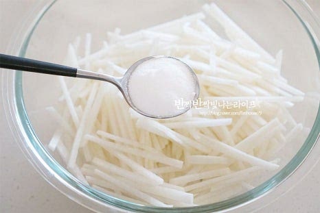 양념을 버무리기 편하도록 넉넉한 크기의 볼에 무채를 넣고 설탕 4 큰 술, 천일염(꽃소금) 1/2 큰 술 정도 넣어줍니다. 소금양은 조절해 넣어주면 됩니다. 양념이 되도록 조물조물 버무려줍니다. 단맛을 먼저 입혀주면 쓴맛을 잡아주고 감칠맛도 깊어집니다. 버무리면 달콤한 간이 스며들면서 수분이 나와 촉촉해집니다.