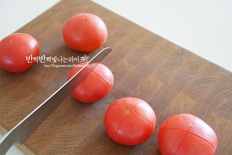 부드럽게 주스 만들기 위해 꼭지 부분이 아래로 향하게 올려놓고 열십자 모양으로 칼집을 넣어줍니다. 껍질째 갈아 마셔도 되지만 살짝 데쳐 제거하면 목넘김이 좋습니다. 냄비에 잠길 정도로 물을 붓고 끓어오르면 칼집 넣은 토마토를 넣어줍니다. 칼집이 물에 닿도록 넣은 뒤 30초~1분 이내로 데칩니다. 너무 오래 데쳐도 물러지면서 풀어지니 겉껍질이 살짝 일어날 정도로 데칩니다. 바로 찬물 또는 얼음 물에서 잔열을 식혀줍니다. 온도차로 인해 자연스럽게 껍질이 벗겨집니다.