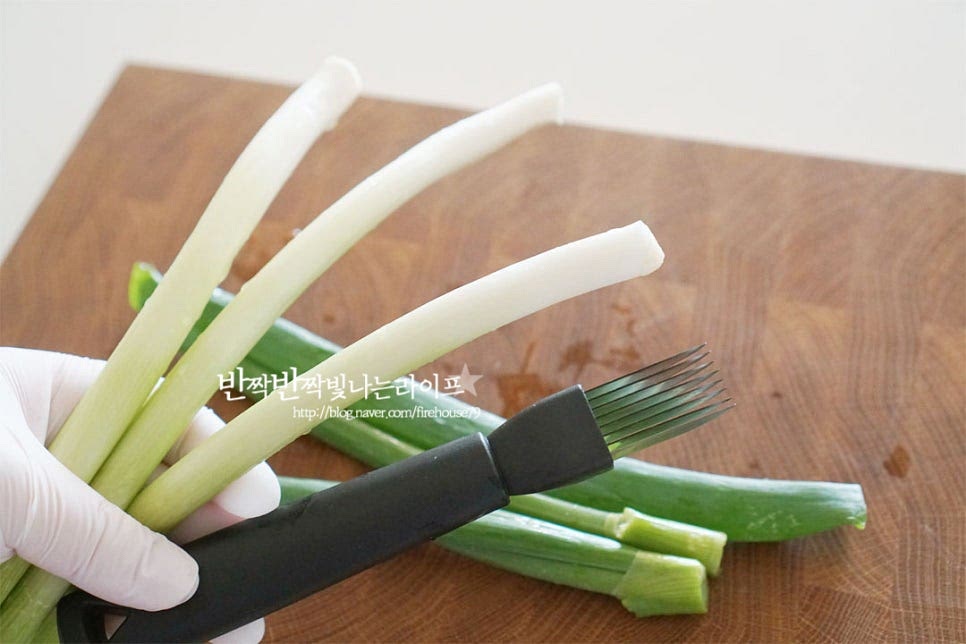 대파는 뿌리 부분을 잘라내고 흐르는 물로 사이사이 깨끗하게 세척해 주었습니다. 파를 먹기좋게 채썬 것을 준비해주거나 저와 같이 직접 칼로 썰어주면 됩니다. 적당한 길이로 나누어 자른 뒤 파채칼로 길이를 따라 썰어줍니다. 자연스럽게 일정한 두께로 나누어지는데 원하는 두께에 따라 한두 번 더 길게 썰어주셔도 좋아요. 그리고 먹기 좋은 길이로 잘라줍니다. 파채칼로 자르지 않고 가늘고 길게 어슷 썰어주거나 길게 반을 갈라 속대를 제거한 뒤 결 방향으로 접어 가늘게 채 썰어주셔도 좋습니다. 초록 부분까지 함께 채를 썰어주면 색감이 훨씬 더 먹음직스러워요. 매운맛에 따라 찬물에 담가 매운맛을 제거하여 요리해 주셔도 좋아요. 헹구어준 뒤 체에 밭쳐 물기를 털어줍니다. 찬물에 헹구어주면 더 아삭합니다.