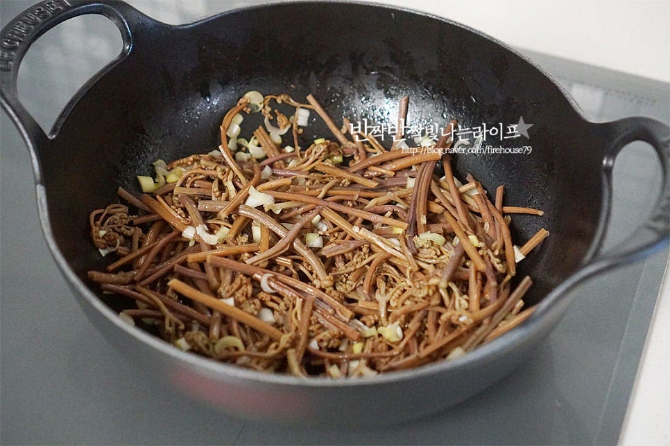 5~10분 정도 밑간해둔 고사리를 불 위에 올려줍니다. 중불 정도에서 2~3분 가볍게 볶아줍니다. 나른하게 볶아지면서 전체적으로 윤기나게 코팅이 되면 멸치 다시마 육수 60ml를 부어줍니다. 육수를 넣고 볶으면 깊은 맛을 낼 수 있으며 쌀뜨물이나 물을 넣어도 좋습니다. 불의 세기에 따라 양은 조절해 주세요. 국물 자작한 상태로 촉촉하게 볶아줍니다. 국물이 자작해질 정도로 부드럽게 볶다가 부족한 간은 소금으로 맞추어줍니다. 쓴맛이나 아린 맛이 느껴진다면 설탕을 한두꼬집 넣으면 됩니다. 수분을 날려 바싹 볶지 않고 국물이 촉촉하게 버무려지는 정도로 볶음을 완성합니다.