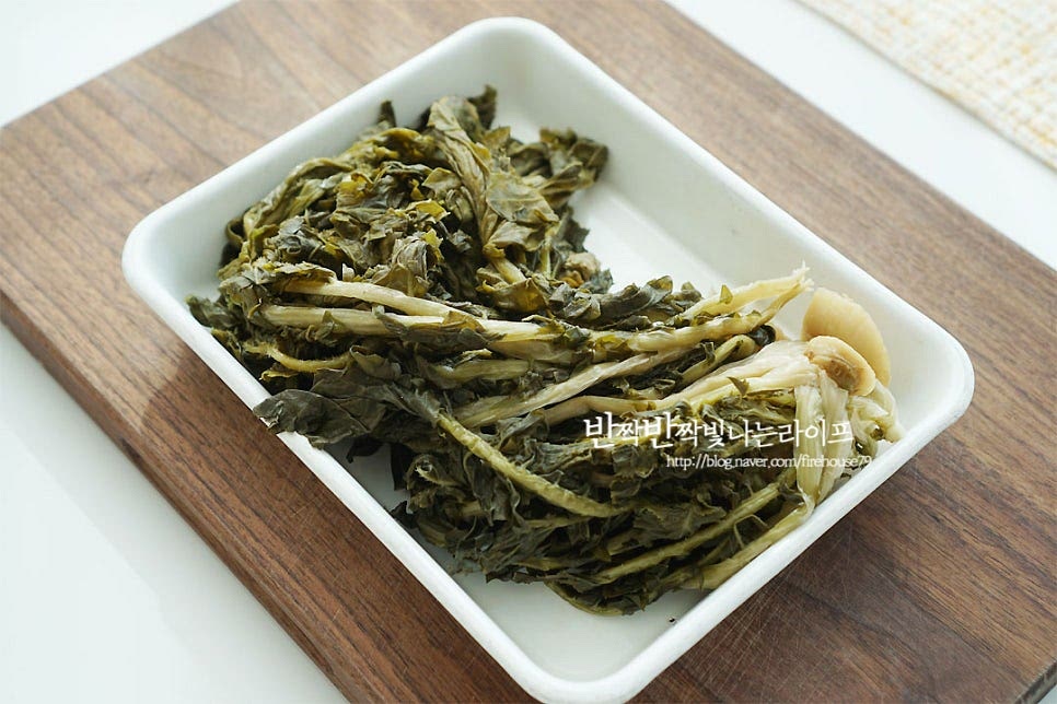 데친시래기를 준비했어요. 요즘은 데쳐서도 잘 나오기 때문에 간편하게 활용하심 좋아요^^ 말린 것은 물에 불린 뒤 삶아주어요. 무청을 말린 것은 영양이 가득하다고 하죠. 예전에는 먹을 게 없어서 말려 먹었다고 하는데 요즘엔 한 번씩 먹음 별미가 따로 없고요. 물에 헹구어 씻어준 뒤 무 윗부분은 가위로 잘라내어 줍니다. 잘 삶긴 것은 줄기 부분을 보면 얇고 투명한 막이 보이는데요. 이 겉껍질을 벗겨 주어야 무청시래기요리를 부드럽게 맛볼 수 있답니다. 손으로 쭈욱 당기면 쉽게 제거할 수 있어요. 그런 뒤 먹기 좋은 크기로 잘라 준비해 줍니다. 밑간을 하여 시래기밥에 넣어주면 구수함이 더 깊어요. 들기름 1 큰 술, 국간장 1 큰 술을 넣어줍니다. 간이 스며들도록 조물조물 버무려주어요. 마침 표고버섯 사둔 게 있어 슬라이스하여 같이 넣어주었어요. 버섯은 선택 재료로 냉장고 사정에 따라 준비해 주세요^^