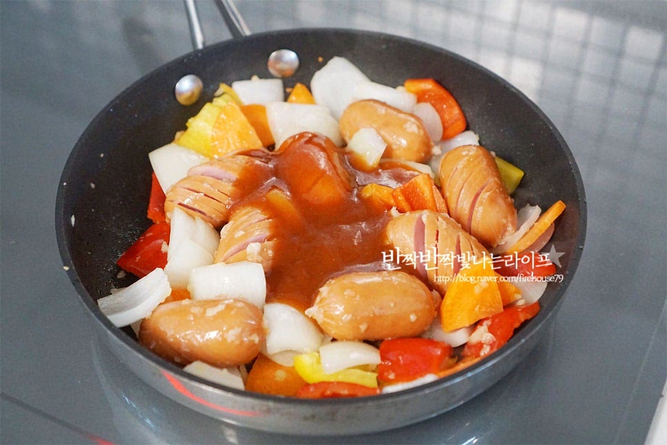 소시지와 야채가 먹기 좋게 익으면 만들어둔 소스를 넣어줍니다. 전체적으로 골고루 어우러지도록 섞은 뒤 칼집 사이사이 양념이 배도록 졸이듯이 볶아줍니다. 농도가 부족하면 물을 약간 더해주셔도 좋습니다. 채소는 오래 익히면 물러질 수 있으니 아삭하게 볶기 위해 중간 센 불로 휘리릭 볶아줍니다. 간이 맛있게 어우러지면 마무리합니다. 쏘야볶음 마지막에 버터 한 조각 넣고 고소한 풍미를 더해주셔도 좋습니다. 소세지야채볶음 레시피 완성입니다.