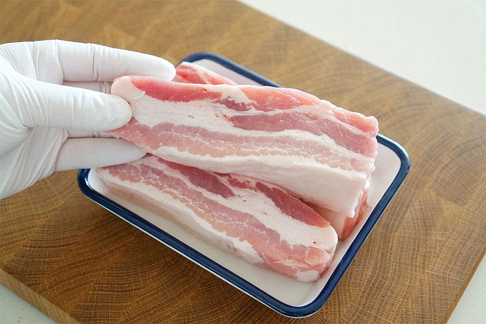 수육을 삶을 때 무난하게 먹기 좋은 부위가 살코기와 비계가 적절하게 섞인 삼겹살이 아닌가 싶어요. 냉장고 사정에 따라 부위는 여러 가지로 만들어도 좋습니다. 막걸리수육은 채소나 물이 들어가지 않는 조리법으로 고깃감과 막걸리만 있으면 간단해요. 깊이가 있는 팬을 달군 뒤 삼겹살을 올려 구워줍니다. 겉면이 노릇노릇해지도록 모든 면을 뒤집어가며 구워줍니다. 먼저 구운 뒤 삶으면 고소한 맛도 풍부해지며 속의 육즙이 새어나지 않아 더 촉촉하고 육즙이 새어나지 않도록 풍미를 살려줄 것이에요. 굽기만 해도 고소함이 가득 느껴집니다.