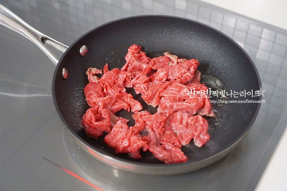 달군 팬에 식용유 1/2 큰 술 두르고 소고기를 올려 익혀줍니다. 기름기가 적은 부위라 식용유 약간 둘러주었는데 생략하고 구워주셔도 좋습니다. 겉면을 살짝 익혀줍니다. 겉이 익으면 채 썬 양파도 같이 넣고 볶아요.