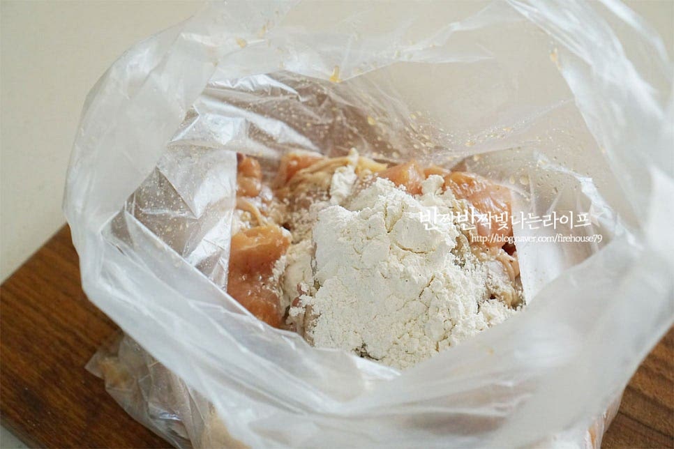 비닐팩에 닭과 함께 튀김가루를 넣어줍니다. 가루 옷을 고르게 입혀준 뒤 식용유 4 큰 술 넣어서 버무려줍니다. 기름에 튀기는 대신 에어프라이어에 구워주기 위해 소량의 식용유를 넣어 겉의 식감을 살려줍니다.