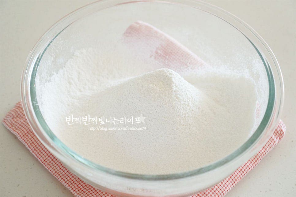 넉넉한 크기의 볼에 박력분, 설탕, 소금, 베이킹파우더를 곱게 체에 내려줍니다. 차가운 무염버터를 넣어줍니다. 버터는 깍둑썰기로 잘라서 냉장 보관해 두었어요. 스콘레시피에서 중요한 팁 중 하나가 반죽에 들어가는 재료는 차가운 상태여야 해요. 그렇기 때문에 모든 재료는 냉장고에 소분해 넣어두었다가 반죽을 섞기 전에 꺼내어 넣어주면 간편하답니다. 가루류와 잘 어우러질 수 있도록 크기를 적당히 작게 썰어두었답니다. 스크래퍼로 잘게 잘라줍니다. 두 개를 동시에 활용하면 빠르게 작업할 수 있으며 푸드프로세서로 섞어주셔도 좋습니다. 버터가 녹지 않으며 쌀알 크기보다 작게 자르듯이 섞어주어요. 잘 섞이면 보슬보슬한 느낌입니다. 만들어둔 차가운 시럽을 꺼내어 계란 1개와 잘 풀어 섞어줍니다. 반죽 가운데 넣어줍니다. 주걱으로 저어가며 한 덩어리가 되도록 뭉쳐줍니다. 작업을 하는 동안 버터가 녹지 않게 해주세요. 한 덩어리가 되면 손으로 뭉쳐줍니다. 이때 손의 열기로 인해 녹지 않게 뭉쳐주세요. 이때 반죽은 손이 묻지 않는 묽지 않은 농도입니다. 비닐팩에 넣고 1시간 냉장실에서 휴지해줍니다.