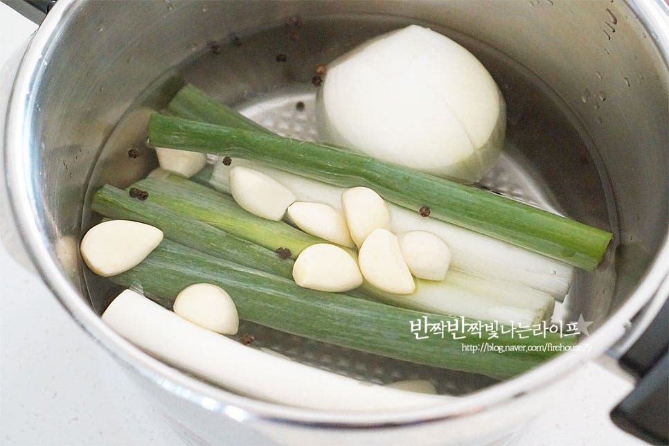 냄비 또는 압력솥을 준비한 뒤 물 1.2L 정도를 붓고 손질하여 준비한 대파, 양파, 생강, 마늘, 통후추를 넣어줍니다. 물의 양은 냄비의 종류나 재료의 양에 따라 조절해 줍니다. 냄비 조리 시 물을 조금 더 넉넉히 잡아주세요. 소고기수육은 향신채소와 함께 깔끔하게 삶아주면 됩니다. 핏물을 제거한 아롱사태, 생강술(청주) 2 큰 술도 같이 넣어줍니다. 재료들을 모두 넣은 뒤 압력솥 뚜껑을 덮고 센불로 끓입니다. 끓으면서 압력추가 올라오거나 흔들리기 시작하면 중약불로 낮추어 30분 정도 삶아줍니다. 냄비로 삶을 때는 1시간 정도 푹 삶아주면 됩니다. 10분 정도 뜸을 들인 뒤 뚜껑을 열어보면 국물이 진하게 우러나고 부드럽게 잘 삶아졌습니다. 뜸을 들인 뒤 육즙이 고르게 퍼지게 하여 썰어서 먹으면 촉촉하고 야들야들합니다. 고기는 부서지지 않게 실온에서 한 김 식힌 뒤 얇게 썰어주세요. 국물은 면포에 한번 걸러 기름을 제거한 뒤 국간장이나 소금 간을 해서 전골 또는 수육으로 준비해 주면 됩니다.