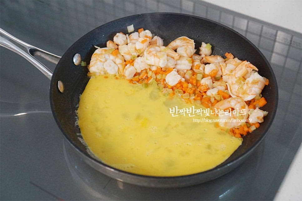 볶은 재료를 한쪽으로 밀어두고 풀어둔 계란물을 부어줍니다. 테두리에서부터 저어가며 고슬고슬하게 볶아줍니다. 볶음밥에 들어가는 계란은 고슬하게 수분을 날려 볶아주면 고소한 풍미를 더 풍부하게 맛볼 수 있어요.