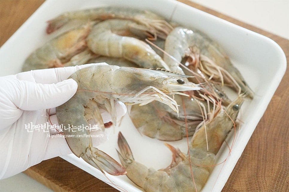 크기가 큼직한 생물 흰다리를 준비했어요. 대하나 블랙타이거와 같은 다른 종류도 알려드리는 레시피로 만들어주면 된답니다. 제철이라 종류 상관없이 달고 살이 올라 맛이 좋은 것 같아요. 새우찜을 먹기 좋도록 먼저 손질을 해주는데요. 머리 부분의 뿔과 입 부분을 가위로 잘라 제거해 줍니다. 뿔이 생각보다 날카롭기 때문에 다치지 않게 주의해 주세요. 몸통을 뒤집어 수염과 다리를 잘라내고 꼬리의 물총도 제거해 줍니다. 두세 마디 사이로 이쑤시개를 찔러 내장을 쭉 당겨 제거해 주어요. 내장을 요리전에 제거하여 주면 쓴맛 없이 고소하게 맛볼 수 있어요. 손질한 뒤 깔끔하게 헹구어 체에 밭쳐 물기를 털어줍니다. 전체적으로 깔끔하게 다듬어주면 쪄서 바로 껍질을 벗겨 먹기만 하면 된답니다~