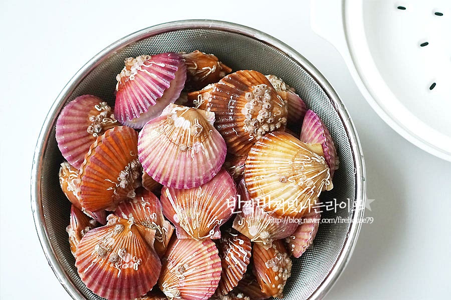 찜기에 쪄줍니다. 찌는법은 물을 자작하게 넣고 끓이는 것과 찜기에 쪄주는 게 있는데 쪄 먹는 게 향이 더 진하고 깊은 것 같아요. 찜기 위에 조개를 올려줍니다. 여기서 첫 번째 포인트가 있는데요, 눕혀서 올려주는 것보다 차곡차곡 세워서 쪄주면 향과 맛도 진하고 하나씩 집어먹기도 편해요. 비스듬히 세워서 올려주면 보기도 좋고 먹기도 좋지요. 익을 때 하나씩 입을 벌리는데 감칠맛이 그대로 담겨서 더 맛있답니다. 가리비찌는법 두 번째 포인트! 찜기에 물을 넘치지 않게 넣고 청주 2 큰 술을 넣어주는 것이에요. 그냥 물에 찌는 것보다는 청주를 넣어주면 특유의 해산물 비린내를 잡아준답니다. 그리고 조갯살도 더 탱글하고요. 끓으면서 조개에서도 수분이 나오므로 찜기 아래 냄비에 물은 끓었을 때 넘치지 않을 정도로 넣어주세요. 저는 400ml 정도 넣어주었어요. 뚜껑을 덮고 15분 정도 쪄줍니다. 너무 오래 찌게 되면 식감이 질겨질 수도 있기 때문에 모두 입을 벌리면 다 익은 거예요. 모두 입을 벌리고 익으면 불을 끄고 5분 정도 뜸을 들여준 뒤 뚜껑을 열어줍니다. 별거 아니지만 뜸을 들여주면 훨씬 더 살이 탱글 해져요. 가지런히 넣은 그대로 하나씩 입을 벌렸어요. 맛있게 잘 익었어요. 재료의 찐맛을 제대로 맛볼 수 있고 집에서 손쉽게 조리할 수 있는 찌는법 영상은 아래를 참고해 주세요. 찌는 동안 청주향이 은은히 나더니 뚜껑을 열었을 때 비린내는 없고 조개 특유의 향이 퍼지는 게 보기에도 먹음직스럽지만 후각적으로도 군침이 돌아요. 제철이라 살이 통통하게 올랐어요. 하나씩 집어먹으면서 이게 겨울의 맛이구나 싶더라고요. 담백하면서도 씹을수록 느껴지는 달큼함이 가리비만의 매력인 것 같아요. 예쁘게 입을 벌린 게 때깔도 참 고와요. 이렇게 쪄 먹으면 아이도 잘 먹어서 온 가족이 열심히 먹방을 한답니다. 찐 다음 버터나 치즈를 곁들여도 정말 맛있어요. 야들야들하면서 탱글 한 식감을 베어 물면 육즙이 톡톡 터지는 게 꿀맛이에요. 아무것도 감미하지 않아도 그 자체에서 나오는 이 맛이 참 맛있어요. 이렇게 한번 쪄먹고 금방 순삭 하고 또 한 번 쪄 먹었어요. 잘 익은 조개는 살이 그대로 분리되어서 먹기에도 좋아요. 레몬즙이나 초장을 곁들여도 맛난답니다. 가리비 찌는법 앞서 말한 포인트를 기억하면 조금 더 맛있고 깊은 맛을 느낄 수 있답니다. 해감 손질한 뒤 찜기에 올릴 때는 세워서 넣어주고, 찌기 전에 청주를 넣어 비린내를 잡아주세요. 입을 모두 벌리면 먹기 좋게 익은 거라 불을 끈 뒤 뜸을 들여준 뒤 먹으면 말이 필요 없는 맛이랍니다. 집에서 요리하기에도 손쉬운 식재료라 겨울철에 꼭 쪄드셔보세요. 끄읕 !