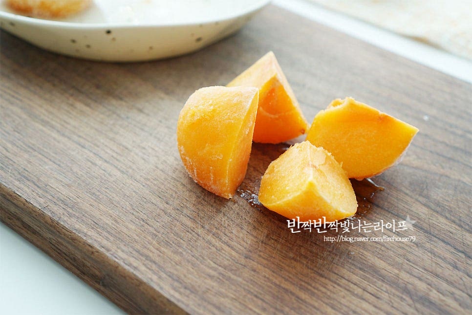 아이스홍시는 갈기 좋도록 4~8등분 하여 줍니다. 냉동실에서 바로 꺼내면 너무 단단하여 손질이 번거로워 실온에 10분 정도 두었어요. 직접 얼려둔 것이라면 열십자로 칼집을 넣어 껍질을 벗긴 뒤 씨를 제거하여 잘라줍니다.