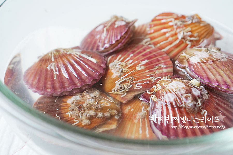 재료를 손질해 줍니다. 가리비는 양식을 할 때 망에 넣어서 하기 때문에 바지락과 같은 조개류와 달리 해감을 꼼꼼하게 해줄 필요는 없어요. 잠길 정도로 물을 붓고 소금 1.5 큰 술을 녹여준 뒤 조개를 넣어주세요. 그리고 30분~1시간 정도 어둡게 덮어두면 된답니다. 해감을 한 뒤 중요한 게 껍데기를 깨끗하게 세척해 주는 것이에요. 조리용 솔로 껍데기 부분을 문질러주면 가루 같은 게 나오는데 흐르는 물로 씻은 뒤 체에 밭쳐 물기를 빼줍니다. 모두 세척하고 나면 이렇게 조갯가루 같은 게 꽤 나오더라고요. 흐르는 물에 씻어내면 말끔해진답니다.