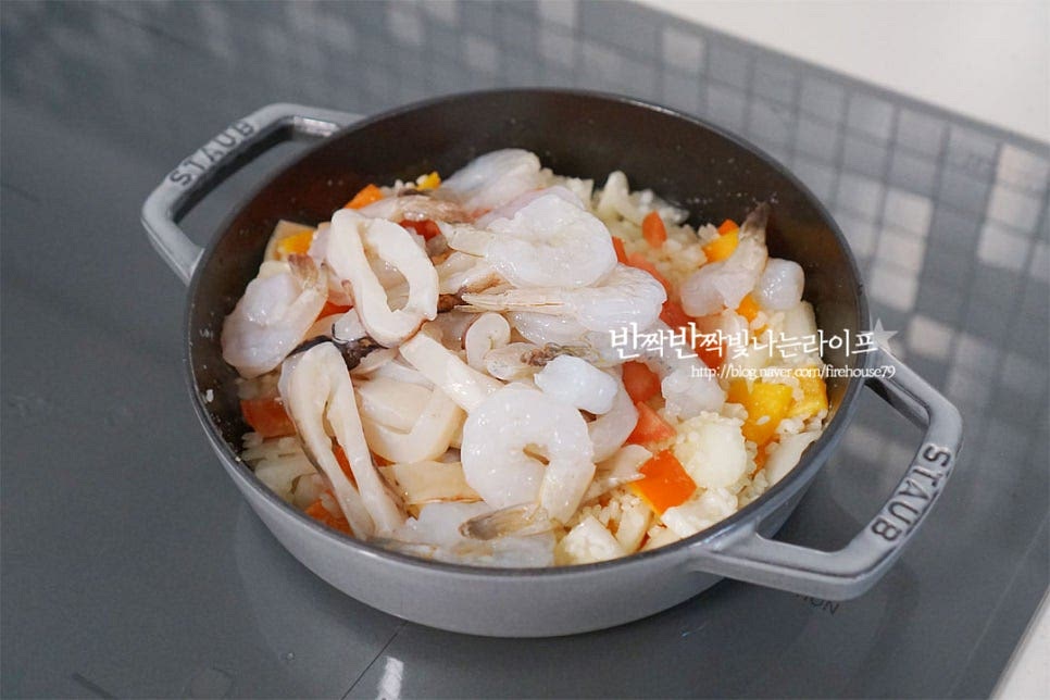 쌀을 볶아 투명빛이 나면 토마토, 새우와 오징어를 넣어줍니다. 겉의 색이 변하고 익을 정도로 3~4분 익혀줍니다.
