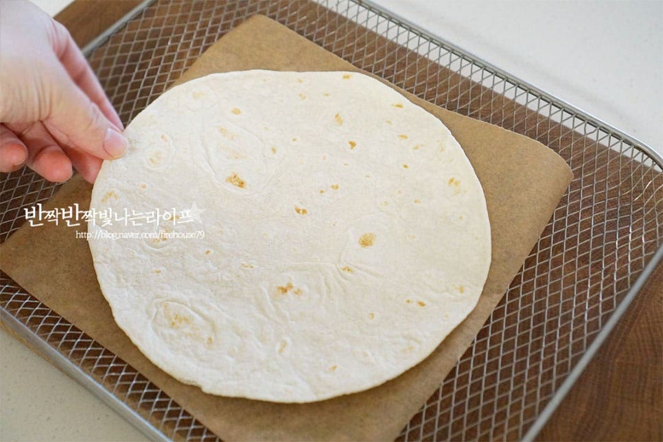 에어프라이어로 구워줄 것이라 트레이에 종이호일을 깔고 바로 또띠아를 올려주었습니다. 그 위로 달콤한 소스를 고르게 발라줍니다. 전체적으로 고르게 모짜렐라치즈도 올려줍니다. 테두리 부분을 넘지 않게 올려주셔야 옆으로 녹아서 흐르지 않습니다. 좋아하는 견과와 건과일을 올려줍니다. 조각 호두, 아몬드 슬라이스, 크랜베리 세 가지를 곁들여 고소하면서도 새콤달콤한 풍미를 더했어요. 생략 가능하지만 함께 넣으면 다채롭게 즐길 수 있어요. 고르곤졸라치즈는 향이 진하기 때문에 양을 너무 많이 넣지 않았습니다. 입맛에 따라 양을 조절해 주세요. 조금씩 뜯어서 간격을 두고 올려줍니다. 전체적으로 재료들이 조화롭게 어우러지게 해줍니다.