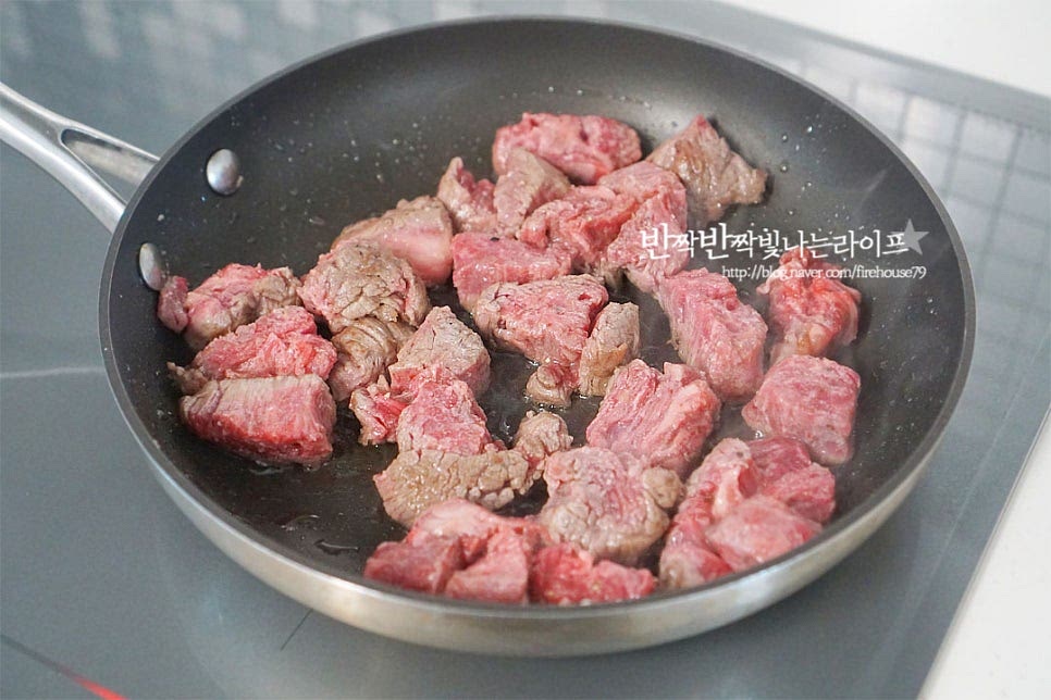 넓은 프라이팬을 센 불로 조절한 뒤 식용유 또는 올리브오일을 넣어줍니다. 밀가루를 뿌린 안심을 넣고 집게로 뒤집어가며 앞뒤로 골고루 익혀줍니다. 겉면이 익어 핏기가 없으면 버터 20g, 마늘을 넣어줍니다. 버터의 고소함이 퍼지면서 그대로 먹어도 맛이 좋아요. 소고기가 버터에 스며들면서 노릇하게 구워줍니다.