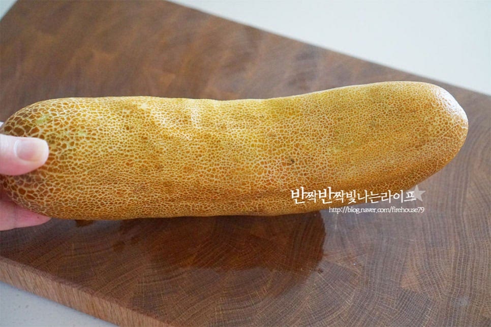 노란빛이 균일하게 돌면서 만져보았을 때 묵직하고 단단한 것이 좋습니다. 크기가 꽤 커서 한 개로 밑반찬 만들면 든든하게 먹을 수 있어요. 겉껍질을 깨끗하게 세척한 뒤 필러로 껍질을 벗겨줍니다. 껍질을 벗긴 뒤 쓴맛이 나는 양 끝은 잘라내어줍니다. 세로 방향으로 길게 반으로 자른 뒤 가운데 씨와 속을 긁어내어줍니다. 오이보다는 씨가 굵고 노각 특유의 쓴맛이 있어 숟가락으로 안쪽 부분까지 깔끔하게 긁어내어 제거했어요.