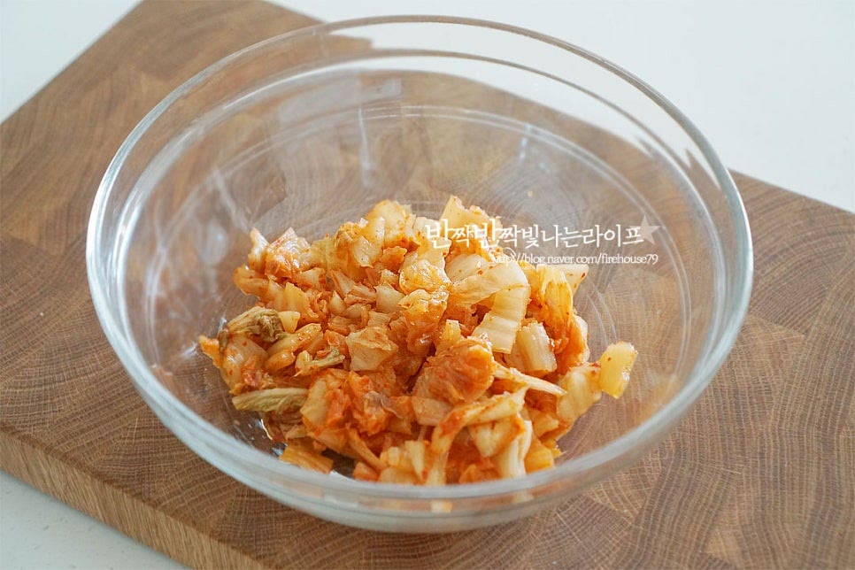 반죽을 만들어 섞을 수 있도록 넉넉한 크기의 볼에 잘게 자른 김치를 넣어줍니다. 대파와 고추, 참치도 함께 넣어줍니다. 매콤함과 맛깔나는 색을 더해주는 고춧가루 1 큰 술, 신맛을 잡아주는 황설탕 1/2 큰 술을 넣어줍니다. 고춧가루는 고운 것을 넣어주면 색이 더 곱게 어우러집니다. 배추에도 단맛이 있기 때문에 설탕은 너무 달지 않게 새콤하게 익은 정도에 따라 양을 조절하여 넣어주면 됩니다. 재료가 어우러지도록 1차로 섞어줍니다. 그럼 고춧가루가 곱게 버무려지고 단맛이 신맛과 섞이면서 감칠맛 나게 양념이 된답니다.