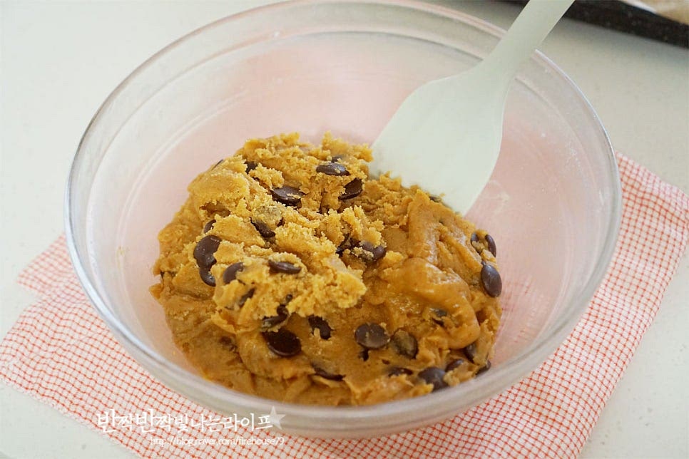 1시간 뒤 꺼내어 보면 조금 더 단단한 느낌이 드는데요. 스쿱이나 주걱으로 나누어 둥근 모양으로 만들어줍니다. 1개당 대략 60g 정도로 소분하여 동그란 모양을 뭉쳐 모양을 잡아주었습니다. 구워지면서 옆으로 퍼지기 때문에 일정한 간격을 두고 팬닝하여 주세요. 초코칩을 위로 올려 모양내면 구웠을 때 더욱 먹음직스러워져요.