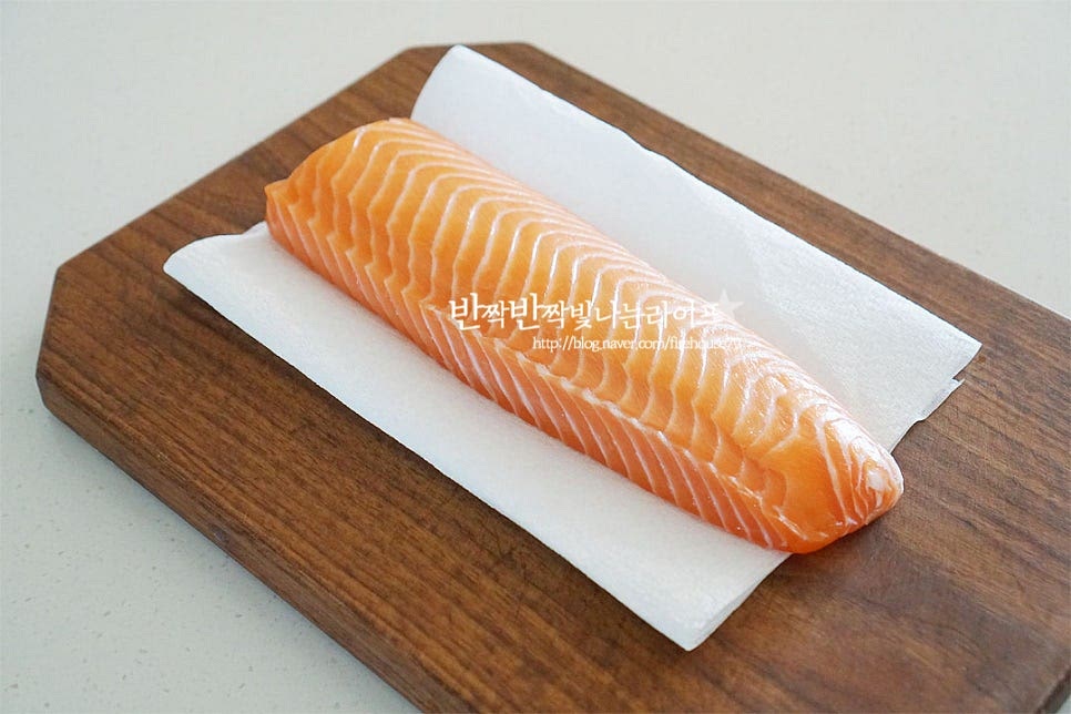 생연어는 필렛을 준비했어요. 요즘은 마트나 온라인에서 쉽게 구할 수 있죠. 생성 종류 중에서도 써는 방법이나 손질이 간단한 편이라 곁들여 요리하기에 좋은 것 같아요. 키친타월로 수분을 제거해 줍니다. 살만 발라진 것이라 그대로 드시면 되지만 수분을 꼼꼼하게 제거하여 주셔야 비린내 없이 깔끔하게 맛보실 수 있어요. 한입에 먹기 좋은 크기로 일정한 두께로 잘라줍니다. 적당히 식감이 느껴지도록 두툼하게 썰어주어요. 얇게 썰면 간이 간간하게 스며들거나 식감이 아쉬울 수 있습니다.