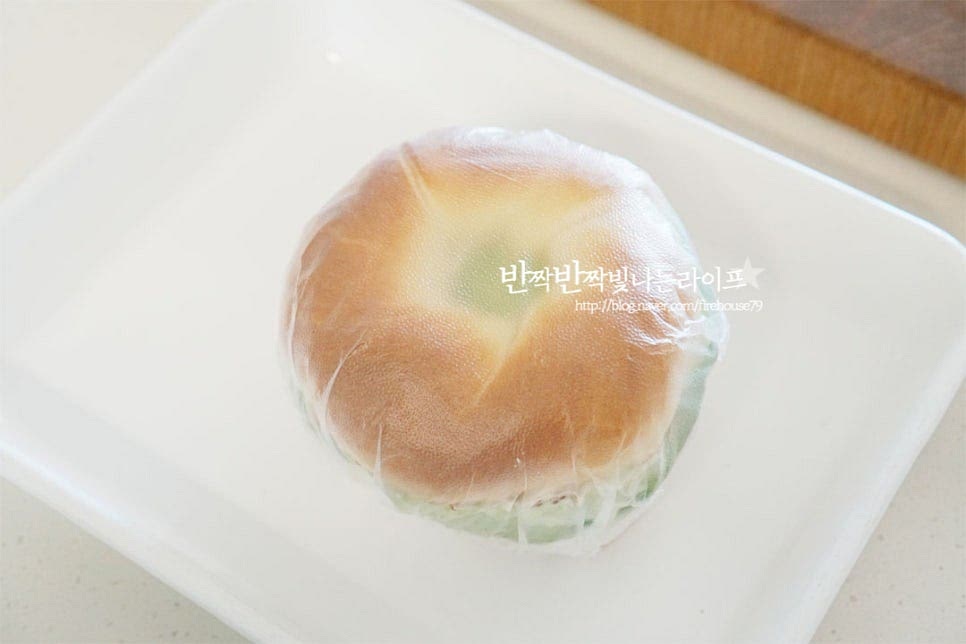 속재료를 푸짐하게 넣어주었기 때문에 손에 들고 먹기 좋게 랩으로 감싸 모양을 고정합니다. 반으로 썰어 베이글샌드위치 만드는법 완성합니다.