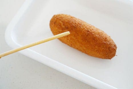 데운 핫도그는 먹기좋게 가운데 나무꼬치를 제거해 줍니다. 가운데 부분에 칼집을 넣어줍니다. 잘리지 않도록 2/3 정도만 칼집을 넣고 가운데를 벌여줍니다. 가운데로 오이와 당근을 넣고 양배추샐러드를 듬뿍 채워줍니다. 야채가 듬뿍 들어가면 아삭아삭 산뜻하게 어울립니다. 마지막으로 케첩을 뿌려 마무리 완성합니다. 간단하게 추억의 간식 만들기 완성되었습니다.