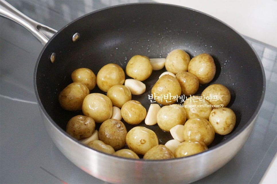 깊이가 있는 팬에 식용유 2큰술 두르고 삶은 감자와 통마늘을 넣고 볶아줍니다. 2~3분 정도 충분히 볶아주시면 식감이 더 좋습니다. 물 200ml, 다시마 한조각을 넣어줍니다. 간장 양념도 넣어주는데요. 진간장 4큰술, 맛술 2큰술 황설탕 1큰술, 고추장 1/2작은술 조청 4큰술 넣어줍니다. 단맛 기호에 따라 설탕은 가감하여 주세요. 고추장을 약간 넣어 매콤하게 색을 살려주었습니다. 다시마는 바글바글 끓으면 3분 정도 있다가 건져내어 주시면 됩니다.