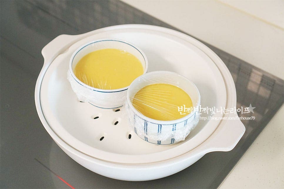 찜기에 올려준 뒤 중탕으로 익혀줍니다. 익힐 때는 온도가 중요한데요. 센 불에 바로 쪄서 익히게 되면 기포가 생길 수 있어 약불로 천천히 익혀주셔야 합니다. 냄비에 물을 넣고 끓기 직전 기포가 올라오기 시작하면 찜기에 올려준 뒤 20분 정도 중탕하여 줍니다. 중간에 15분 정도 익힌 뒤 새우를 올려 5분 더 쪄주었어요. 곁들이는 고명은 새우나 게살, 당근, 고추 등 기호에 따라 준비하여 주시면 됩니다. 중간에 고명을 올릴 때는 랩을 열면서 물이 들어가지 않게 조심하여 주세요. 20분 중탕하여 익히면 탱글탱글 매끈한 질감으로 뽀얗게 잘 익어있어요. 기포 없이 매끈하게 잘 익었어요. 몽글몽글 어우러지는 맛도 좋아하지만 이렇게 입안에서 사르르 녹는 촉촉한 맛도 매력이죠. 그릇을 살짝 흔들어보면 보드라우면서도 탄력 있게 잘 만들어졌어요. 영상도 같이 담았어요. 숟가락으로 떠서 먹음 부드러운 식감에 반하는데요. 아이 어른 할 것 없이 모두가 먹기 좋은 맛이랍니다. 부드러운 계란찜 맛있게 만들어 드세요^^ 끄읕 !