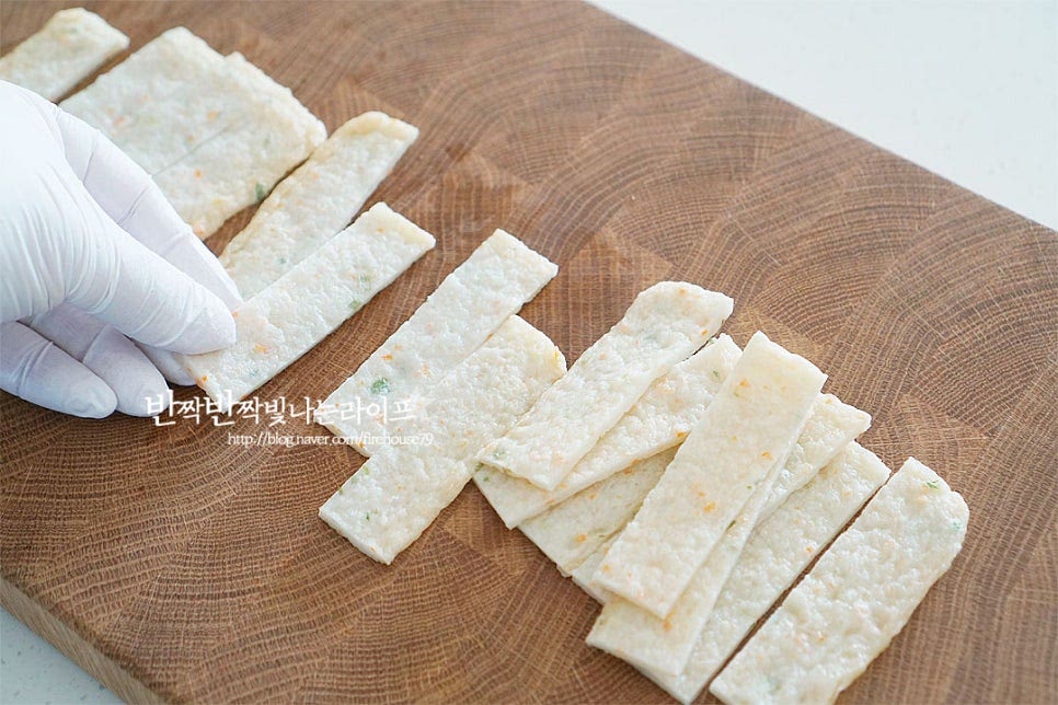 어묵에 들어가는 생선과 야채에 따라 맛과 모양이 다양한 편인데요. 기본 납작한 사각을 준비해 줍니다. 끓는 물에 살짝 데쳐 기름기를 제거해 먹기도 하지만 바삭하고 쫄깃한 어묵튀김을 만들어줄 것이라 그대로 요리해주었습니다. 크기에 따라 일정한 너비로 길게 잘라줍니다. 대략 1.5~2cm 너비로 잘라주었어요. 양 끝 부분을 넉넉하게 띄운 뒤 가운데 칼집을 길게 넣어줍니다. 네모난 모양 그대로 어묵칩을 만들어도 맛있지만 꽈배기처럼 트위스트로 만들면 식감도 바삭하고 먹음직스럽답니다. 가운데 칼집을 넣은 부분을 벌린 뒤 아랫부분을 그 사이로 넣어주면 간단한 방법으로 만들 수 있어요. 이 방법으로 여러 개를 만들어줍니다. 어린 시절 학교 앞에서 나무 꼬치에 어묵을 꽂아서 튀겨서 팔곤 했는데 그 느낌도 나는 게 맛이 좋아요.