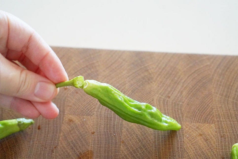 꽈리고추는 세척한 뒤 물기를 제거하고 먹기 좋도록 꼭지를 잘라줍니다. 씻은 뒤 꼭지를 제거해 주어야 물러지지 않게 식감을 살릴 수 있습니다. 크기에 따라 한입에 집어먹기 좋도록 2~3등분으로 잘라주셔도 좋아요. 얼큰한 향이 진하게 나오고 간이 맛있게 스며들 수 있도록 포크를 사용하여 콕콕 찔러줍니다. 나무꼬치를 활용해도 되어요. 마늘은 편으로 썰고 홍고추는 송송 썰어줍니다. 다진마늘을 넣어도 되지만 입자가 고와 타기 쉬우므로 편마늘을 넣어 향도 살리고 식감도 맛있게 요리해요.