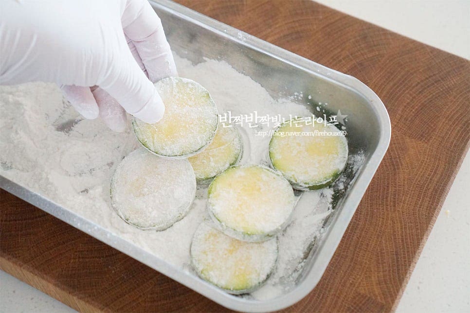 넓은 볼에 부침가루 3~4 큰 술을 뿌리고 밑간해둔 애호박에 부침가루 옷을 입혀줍니다. 뭉치지 않고 균일하게 털어가며 입혀주세요.