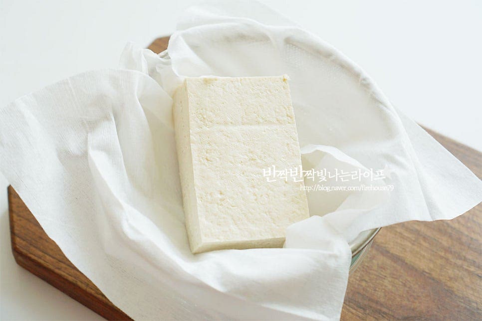 톳두부무침의 맛 비결은 두부의 담백 고소함이죠~ 두부는 수분을 완전히 제거해 주어야 무침을 만들었을 때 물이 생기지 않아요. 그렇기 때문에 면포에 넣고 물기를 꼭 짜줍니다. 면포를 꼭 짜서 수분을 제거했어요. 물기를 제거하다 보면 칼로 으깨어줄 필요 없이 자연스럽게 으깨어진답니다.